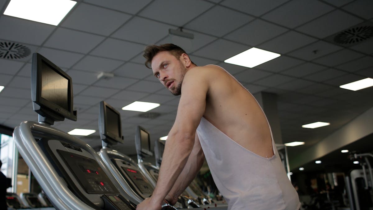 A focused man exercising on a treadmill in a modern gym setting, showcasing dedication and fitness.